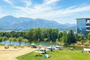 A campsite with tents and RVs by a lake with mountains in the background. - Wei Select Xueye Hotel (Jinan)