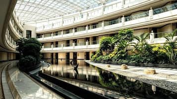 Een atrium met meerdere niveaus, een centraal waterbassin, balkons en beplanting.