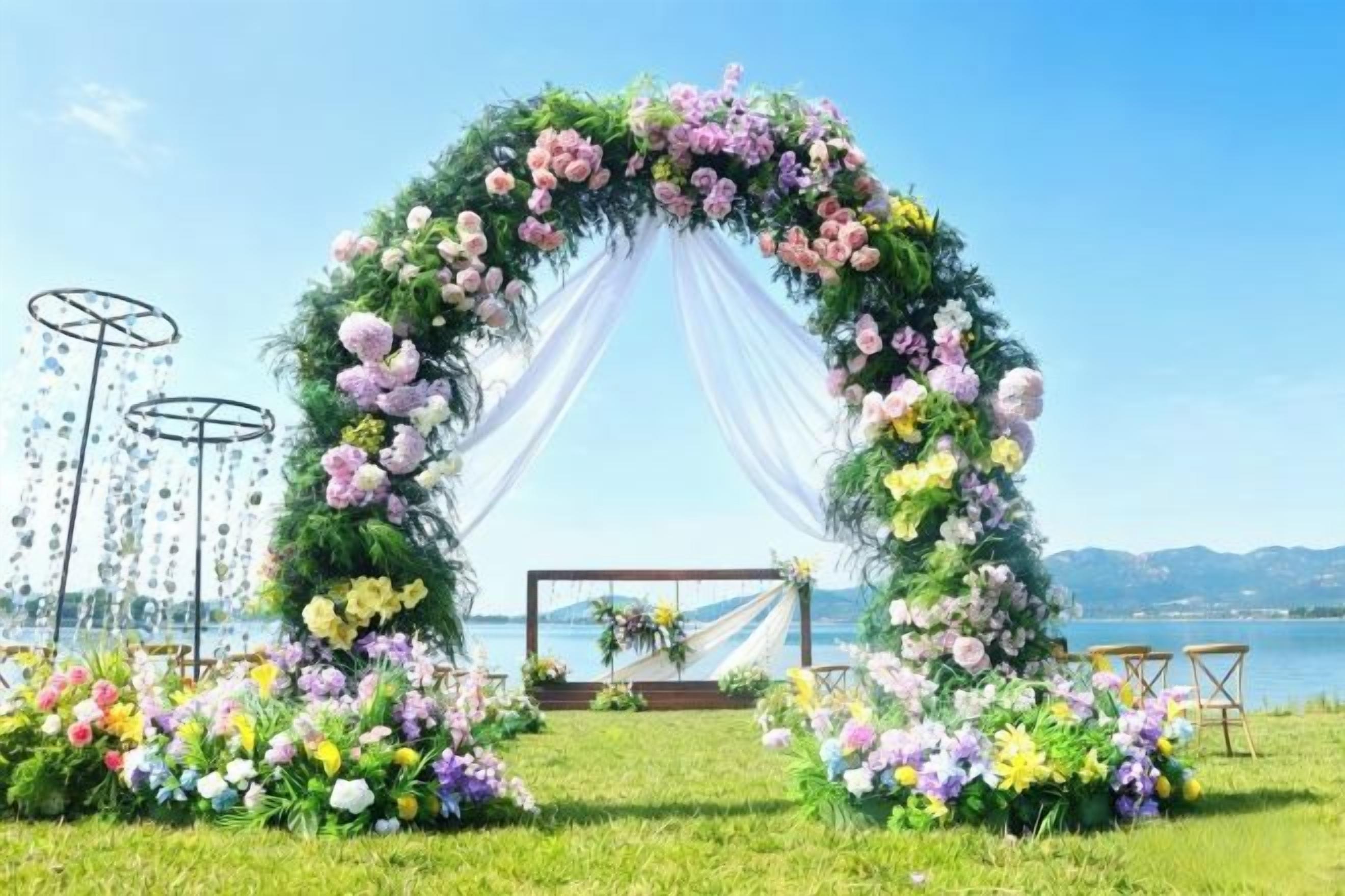 An outdoor wedding arch with floral decorations, a grassy area, and a body of water in the background.