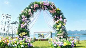 An outdoor wedding arch with floral decorations, a grassy area, and a body of water in the background.