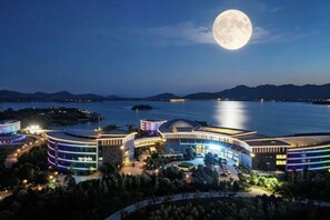 A hotel with a waterfront view, a crescent moon in the sky, and a body of water in the background. - Wei Select Xueye Hotel (Jinan)