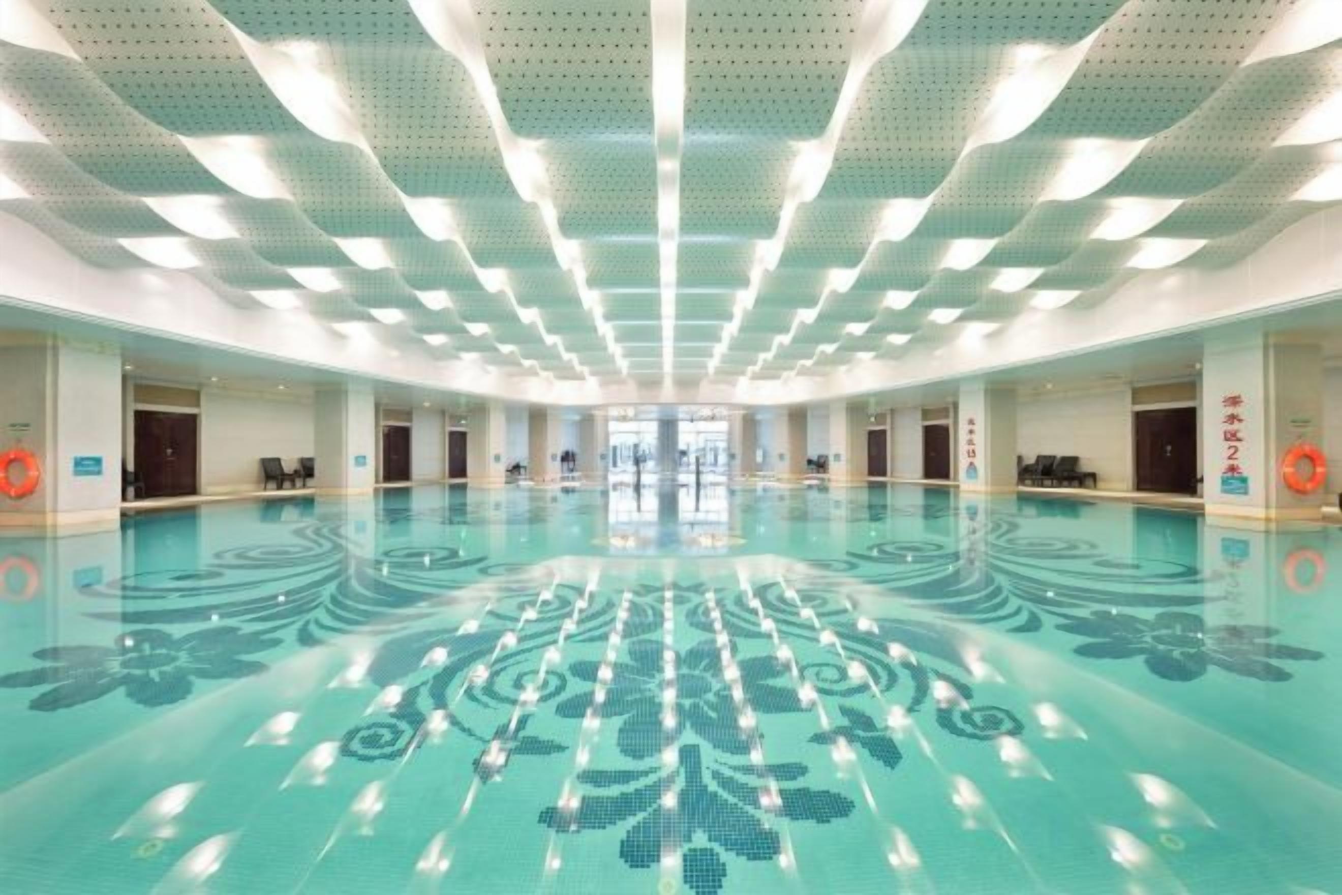 A large indoor swimming pool with a central viewing area, surrounded by multiple doors and windows.