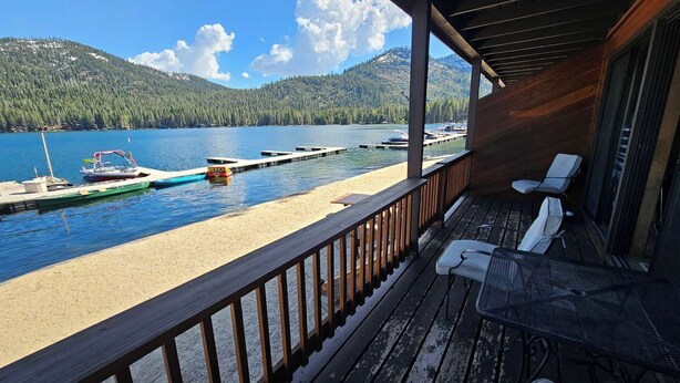 A wooden deck with a view of a lake and docked boats. - Lakeside Condo at Donner Lake - 2 Bdrm. 2 Bath - 1st floor - steps from the lake (Truckee)