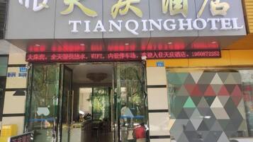 The exterior of Tianqing Hotel with a glass entrance, signage in both Chinese and English, and a visible restaurant area inside.