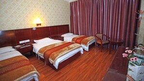 A hotel room with two beds, a wooden headboard, a nightstand, a desk, a chair, a lamp, and a curtain. - Tiancheng Hotel (Dali City)
