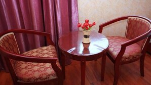 A room with a round wooden table, two patterned chairs, and a vase with red flowers. - Tiancheng Hotel (Dali City)