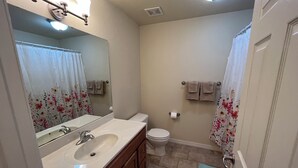 Ein Badezimmer mit Waschbecken, Spiegel, Toilette und Duschvorhang.