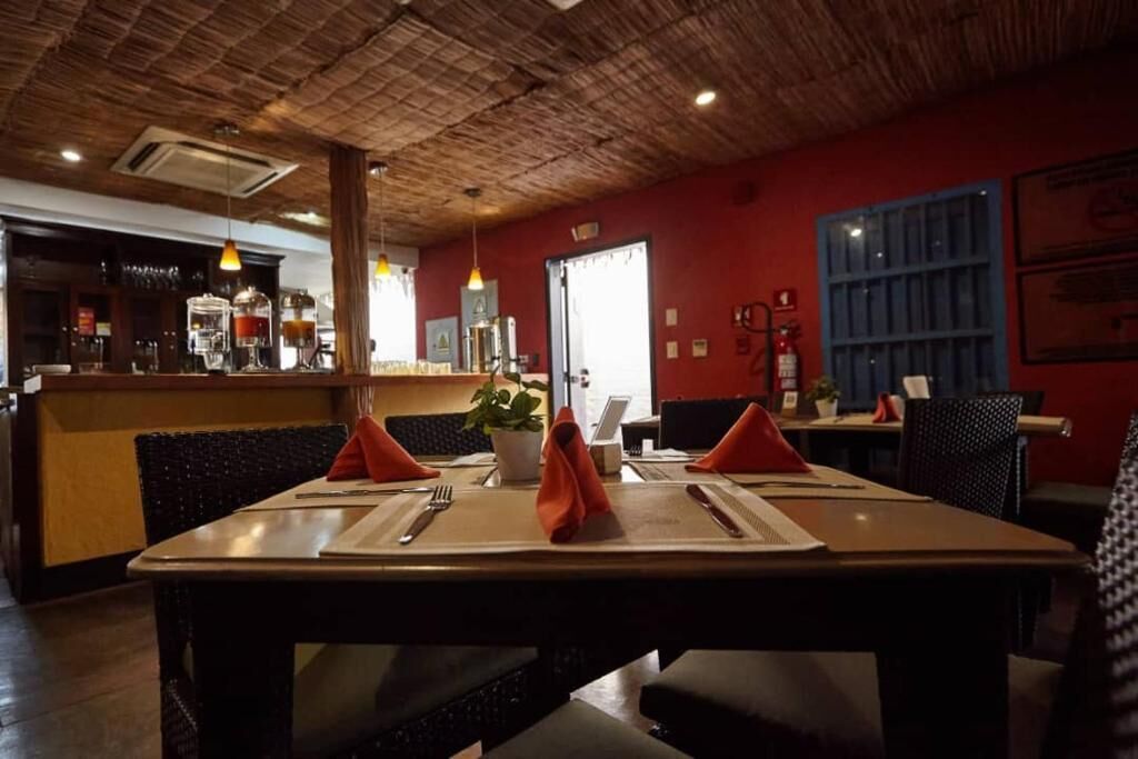 Ein Restaurant mit Holzbalkendecke, roten Wänden und einer Bar im Hintergrund.