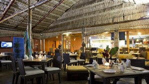 Un restaurante con techo de paja, muebles de mimbre y una zona de bar.