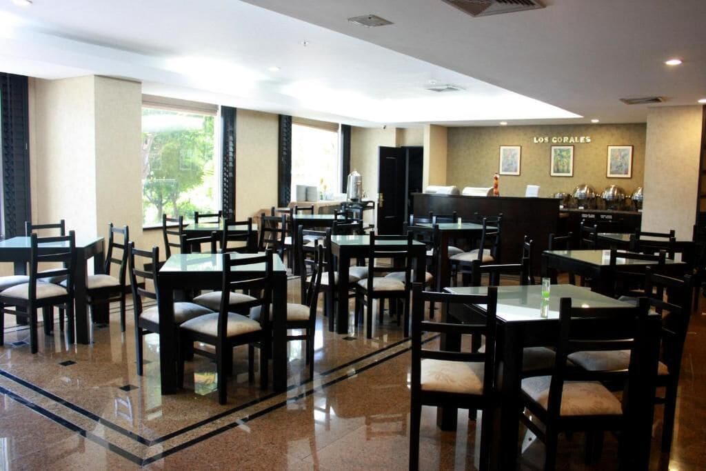 A spacious restaurant with multiple tables and chairs, a counter with a menu, and a wall with framed pictures.