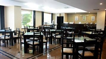 Ein geräumiges Restaurant mit mehreren Tischen und Stühlen, einer Theke mit Speisekarte und einer Wand mit gerahmten Bildern.