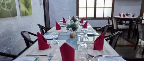 A dining area with tables set for service, featuring white plates, cutlery, and red napkins.
