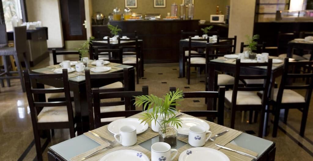 A dining area with multiple tables set for breakfast, including plates, cups, and cutlery.