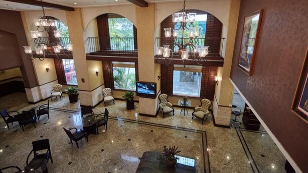 Un vestíbulo amplio con techos altos, candelabros, asientos cómodos y ventanas grandes que ofrecen vistas al exterior.