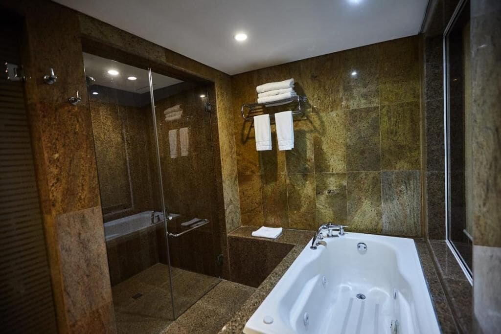 A modern bathroom with a glass-enclosed shower, a freestanding bathtub, and a towel rack with folded towels.