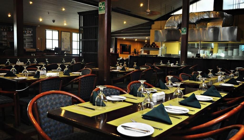 A restaurant with multiple tables set for dining, chairs, and a kitchen area in the background.
