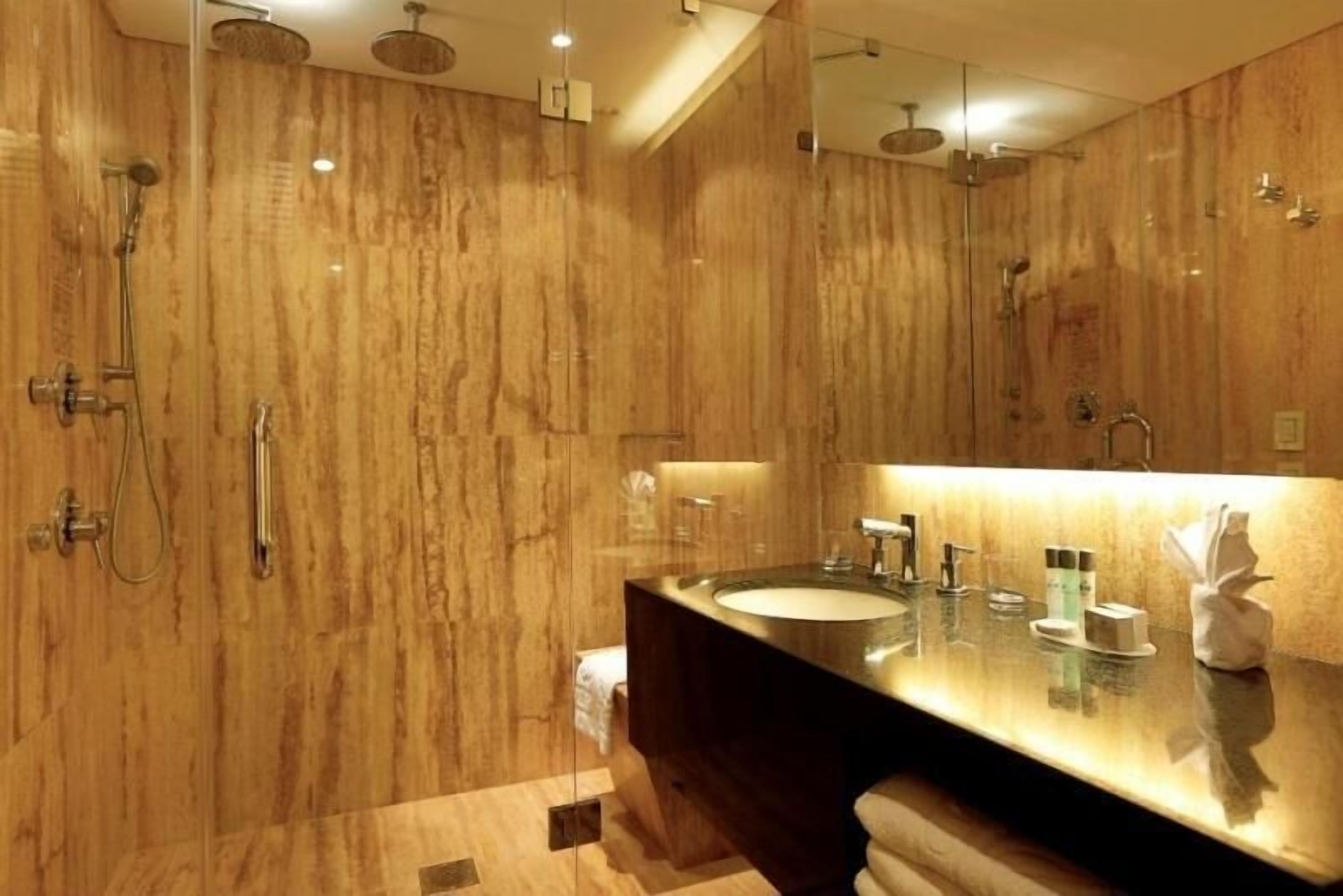 A modern bathroom with a large mirror, a sink, and a shower area.