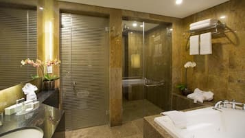A modern bathroom with a glass-enclosed shower, a large bathtub, and a vanity with a mirror and sink.
