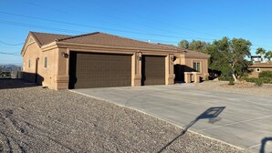 Une maison à deux étages avec une façade marron, deux portes de garage et une allée.