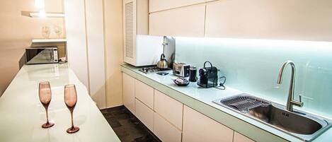 A modern kitchen with a long countertop, a sink, and a microwave.