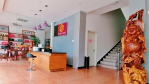 A reception area with a wooden desk, a staircase, and a large Buddha statue. - Dongnan Express Hotel (Wuyishan)