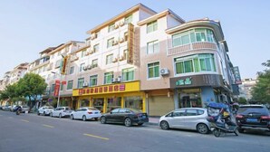A multi-story building with a yellow storefront and a blue awning. - Dongnan Express Hotel (Wuyishan)