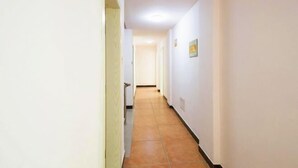 A narrow hallway with white walls and a tiled floor, leading to a door at the end. - Dongnan Express Hotel (Wuyishan)