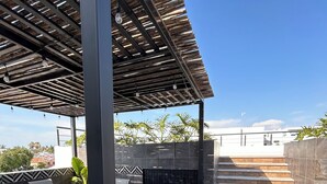 En uteplats med en pergola, en sittgrupp och utsikt över en byggnad i bakgrunden.