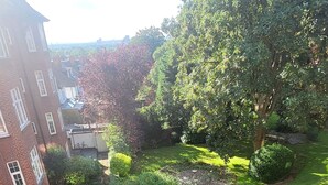 A well-maintained garden with a lawn, a small flower bed, and a brick building with multiple windows.