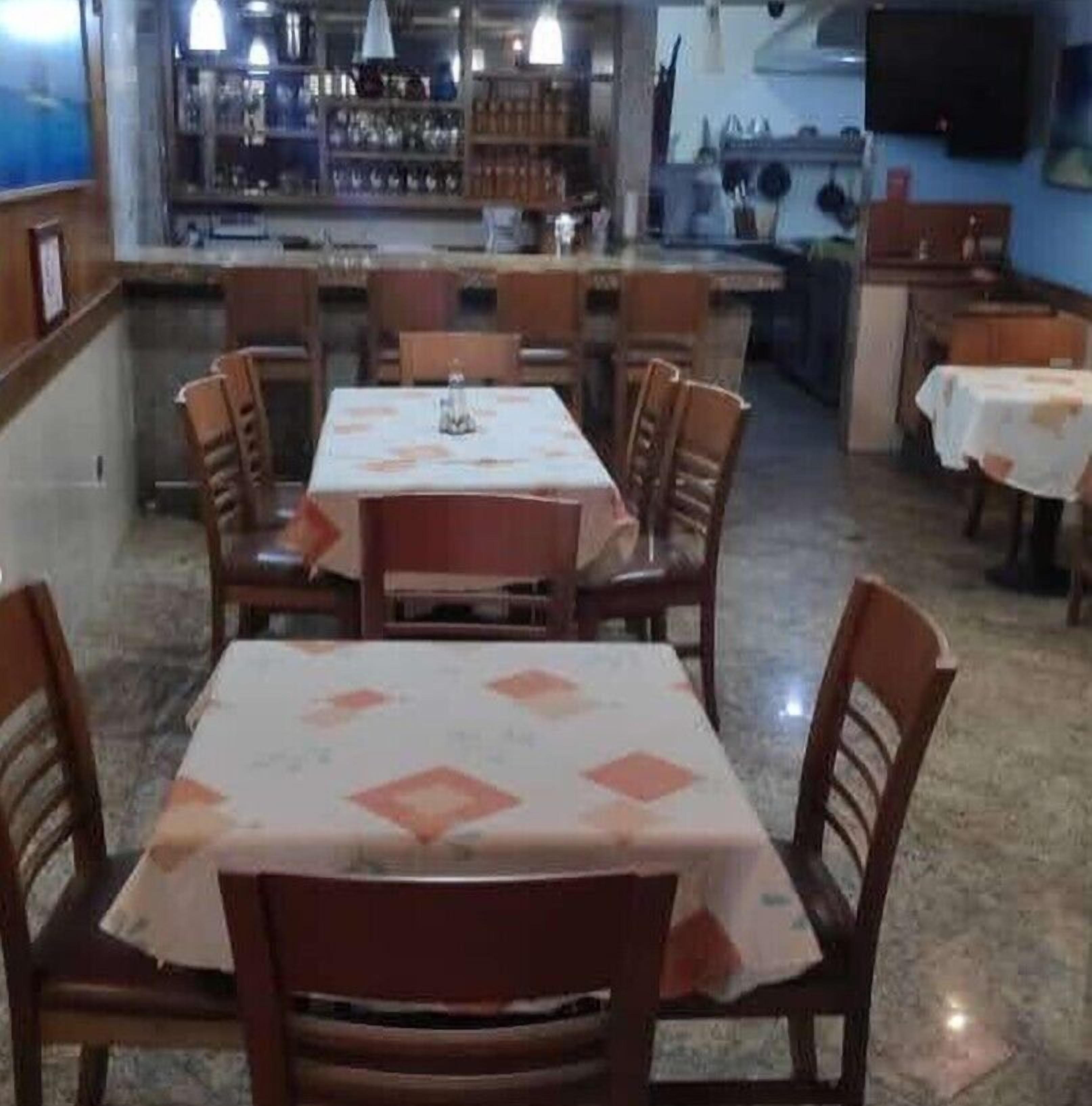A dining area with a central table and chairs, a kitchen in the background, and a bar area with shelves and bottles.