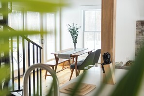 A dining area with a wooden table and chairs, a vase with greenery, and a stone wall.