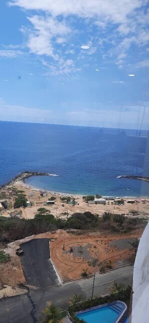 A coastal view with a beach, a swimming pool, and a clear sky. - HOTEL MIRAMAR SUITES (Urimare)