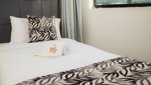 A hotel room with a bed, a window with a view, and an air conditioning unit. - HOTEL MIRAMAR SUITES (Urimare)
