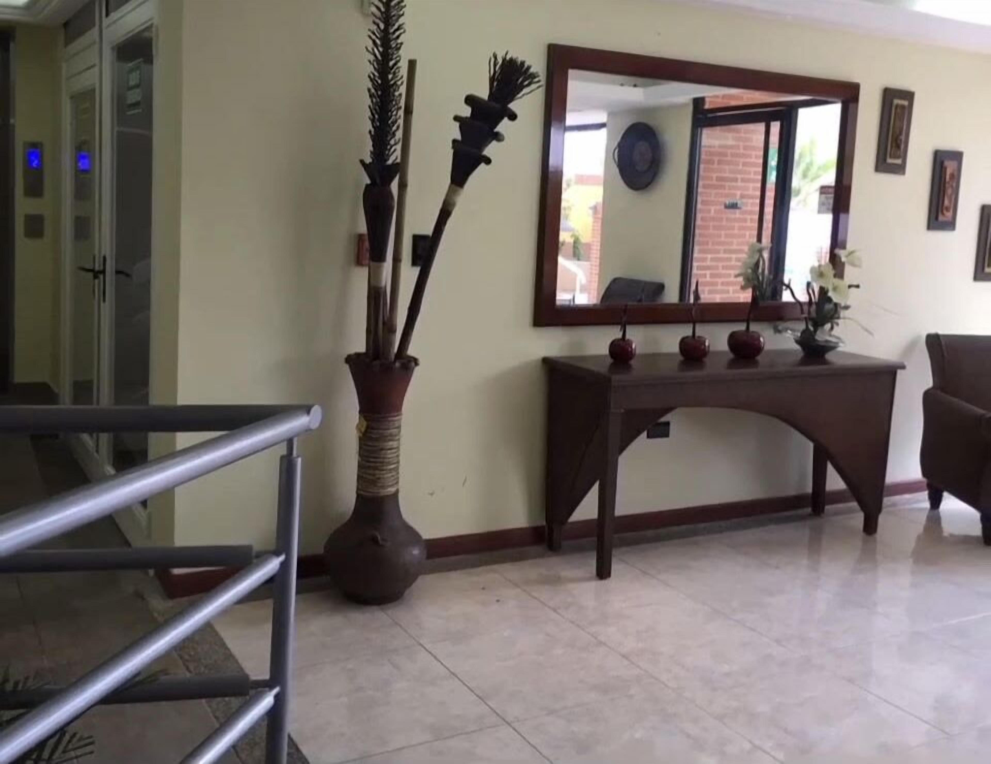 A reception area with a desk, a mirror, and a vase with decorative items.