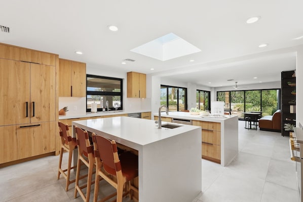 Una cocina moderna con una isla central, armarios de madera y un tragaluz.