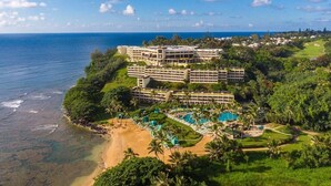 Ein Hotel direkt am Strand mit mehreren Gebäuden, einem Pool und üppiger Vegetation.