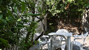 A table and chairs set outdoors with a gravel ground, surrounded by greenery and a white wall. - S343 - Sirolo, new three-room apartment with a/c and parking space (Sirolo)