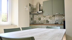 A modern kitchen with green cabinets, a marble countertop, and a dining area with a table and chairs. - S343 - Sirolo, new three-room apartment with a/c and parking space (Sirolo)