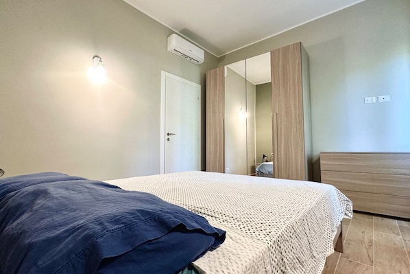 Une chambre à coucher comprenant un lit, une armoire, un miroir et un appareil de climatisation.