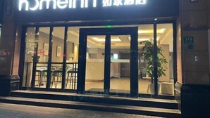L’entrée d’un hôtel avec une façade en verre, une enseigne indiquant « Homeinn » et un numéro d’adresse bien visible, le « 370 ».