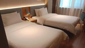 Une chambre d’hôtel avec deux lits, une table de chevet avec une lampe et une fenêtre avec des rideaux.