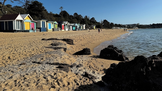 Une plage avec des cabanes colorées et une rive sablonneuse.