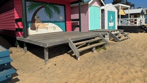 Une rangée de cabanes de plage avec une terrasse en bois à l’avant.