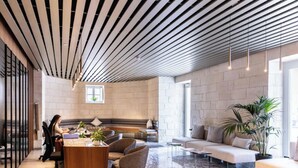 Ein modernes Interieur mit einer querverlegten Decke, einer Sitzecke mit Sofas und einem Couchtisch sowie einem großen Fenster, das für natürliches Licht sorgt.