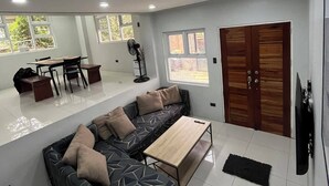 A modern living room with a sofa, a coffee table, and a dining area with chairs and a table. - A quiet and amazing place with mountain view and cool breeze of Baguio City. (Baguio City)