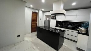 A modern kitchen with white cabinetry, a black island, and a stainless steel range hood. - A quiet and amazing place with mountain view and cool breeze of Baguio City. (Baguio City)
