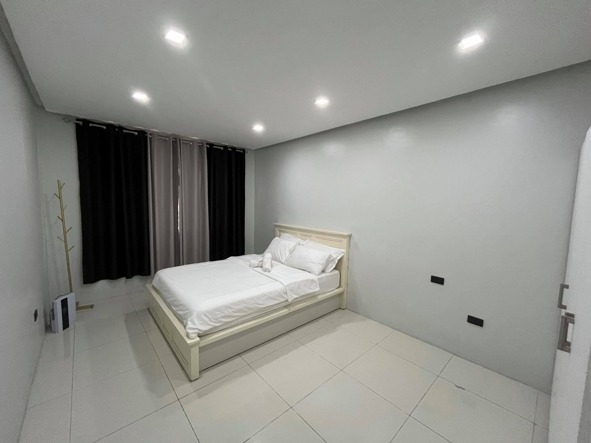 Une chambre à coucher avec un lit, des rideaux, un radiateur et un luminaire fixé au mur.