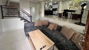 A modern living room with a sofa, a wooden coffee table, and a staircase. - A quiet and amazing place with mountain view and cool breeze of Baguio City. (Baguio City)