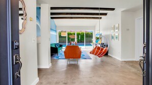 A modern interior with a large window, a hanging chair, and a sofa. - Stunningly designed, colorful, fun 3-bedroom house in Central Palm Springs. (Palm Springs)