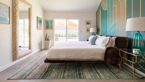 A bedroom with a large bed, a mirror, and a view of the outside. - Stunningly designed, colorful, fun 3-bedroom house in Central Palm Springs. (Palm Springs)